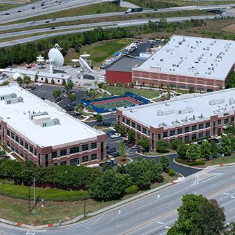 Aerial view of the Viasat campus in Deluth, Georgia with 3 office buildings, 7 satellite antennas and a tennis court